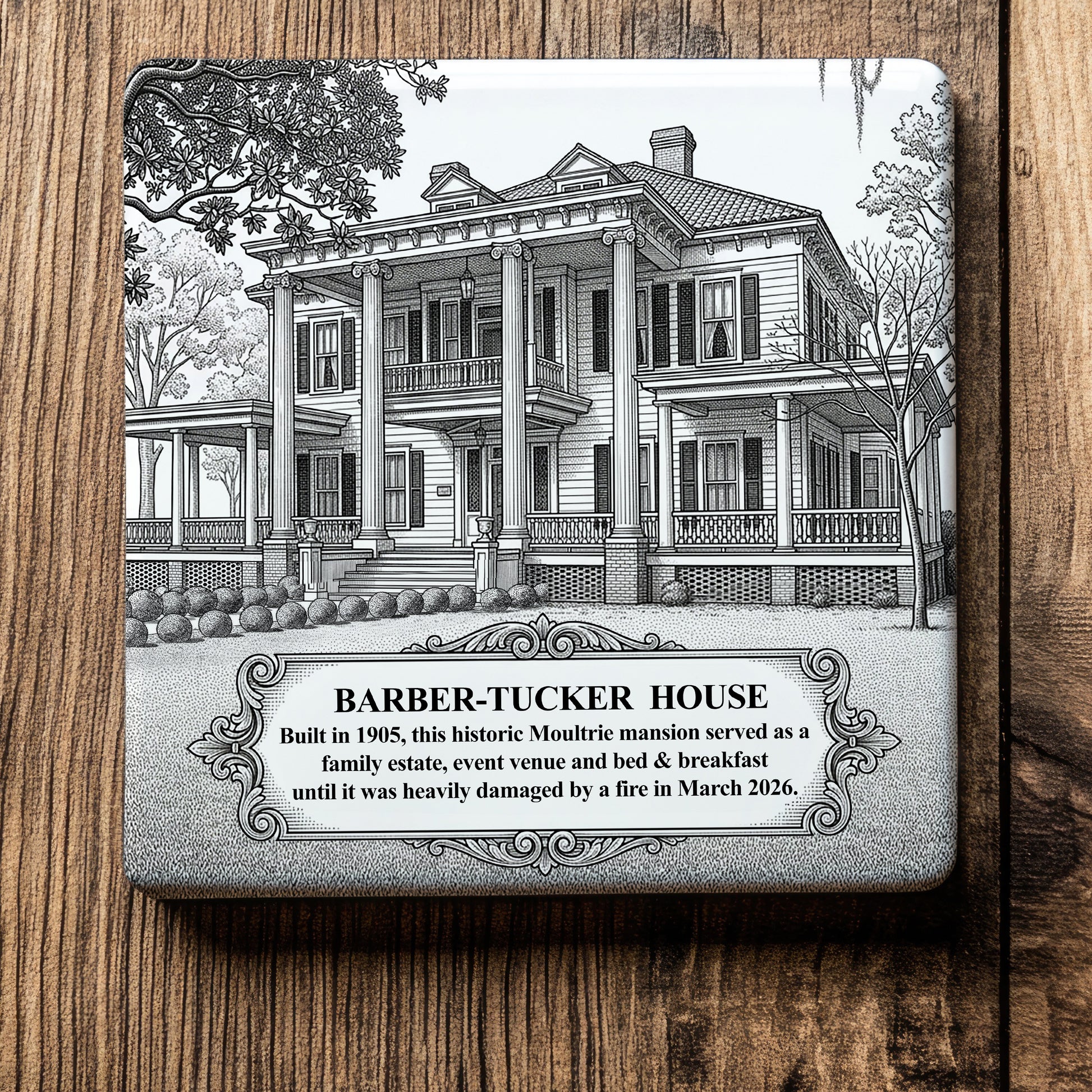 White ceramic coaster with a vintage pen-and-ink engraving of the 1905 Barber-Tucker House in Moultrie, Georgia. Displayed flat on a rustic wooden table background.