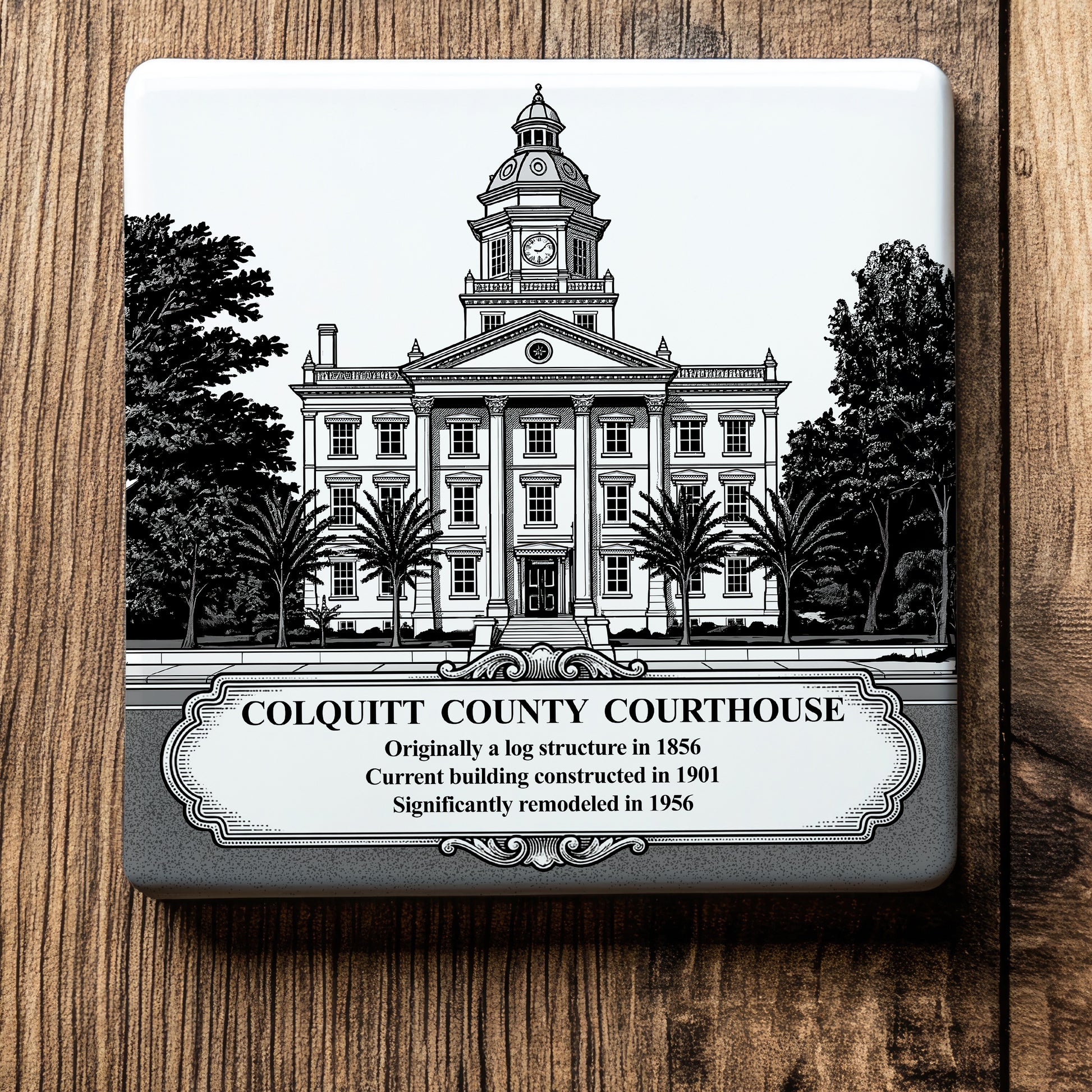White ceramic coaster with a vintage pen-and-ink engraving of the historic Colquitt County Courthouse in Moultrie, Georgia. Features the landmark's clock tower, columns, and a historical timeline banner, displayed flat on a wood background.