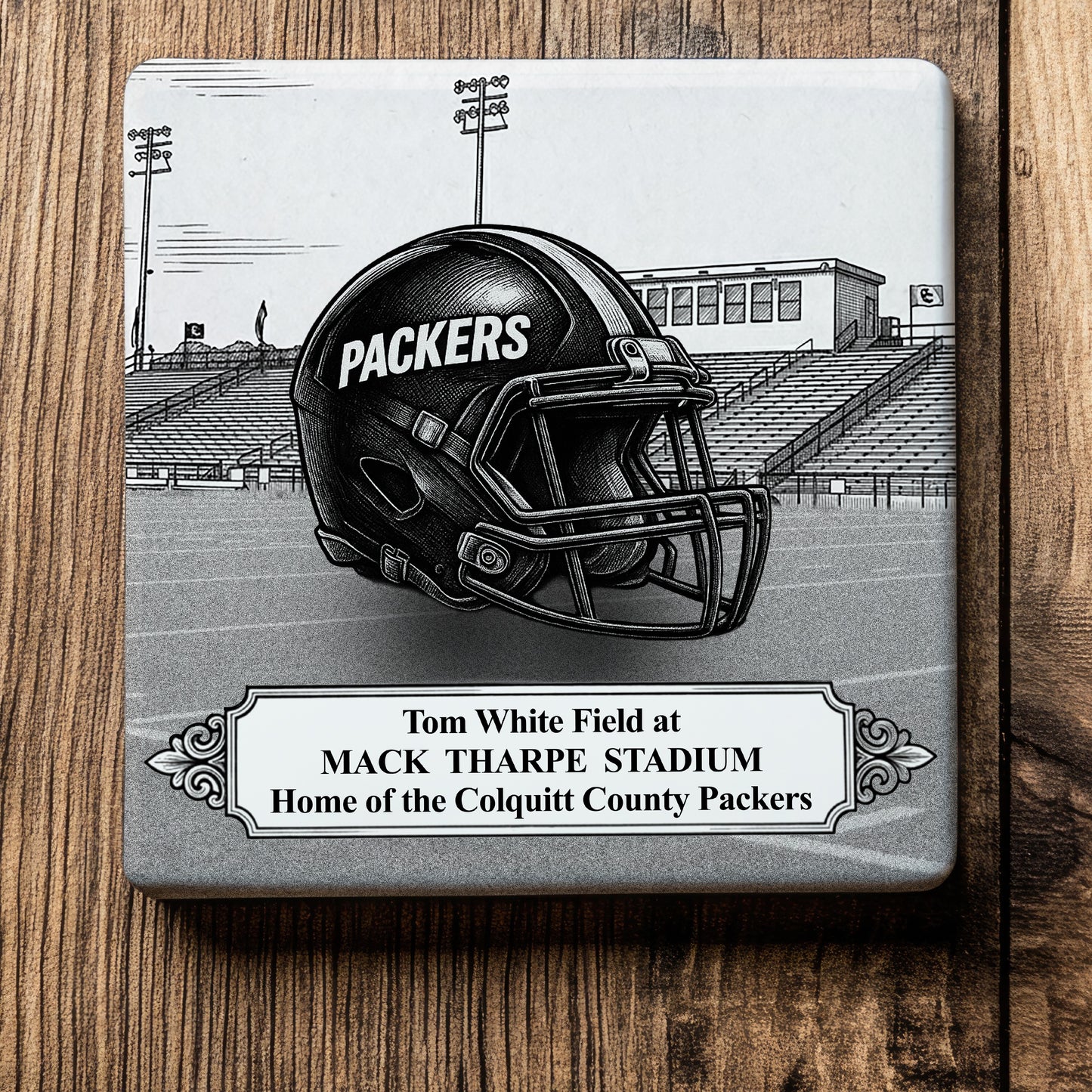 Ceramic drink coaster featuring a detailed black-and-white illustration of a Colquitt County Packers football helmet on Tom White Field at Mack Tharpe Stadium in Moultrie, Georgia.