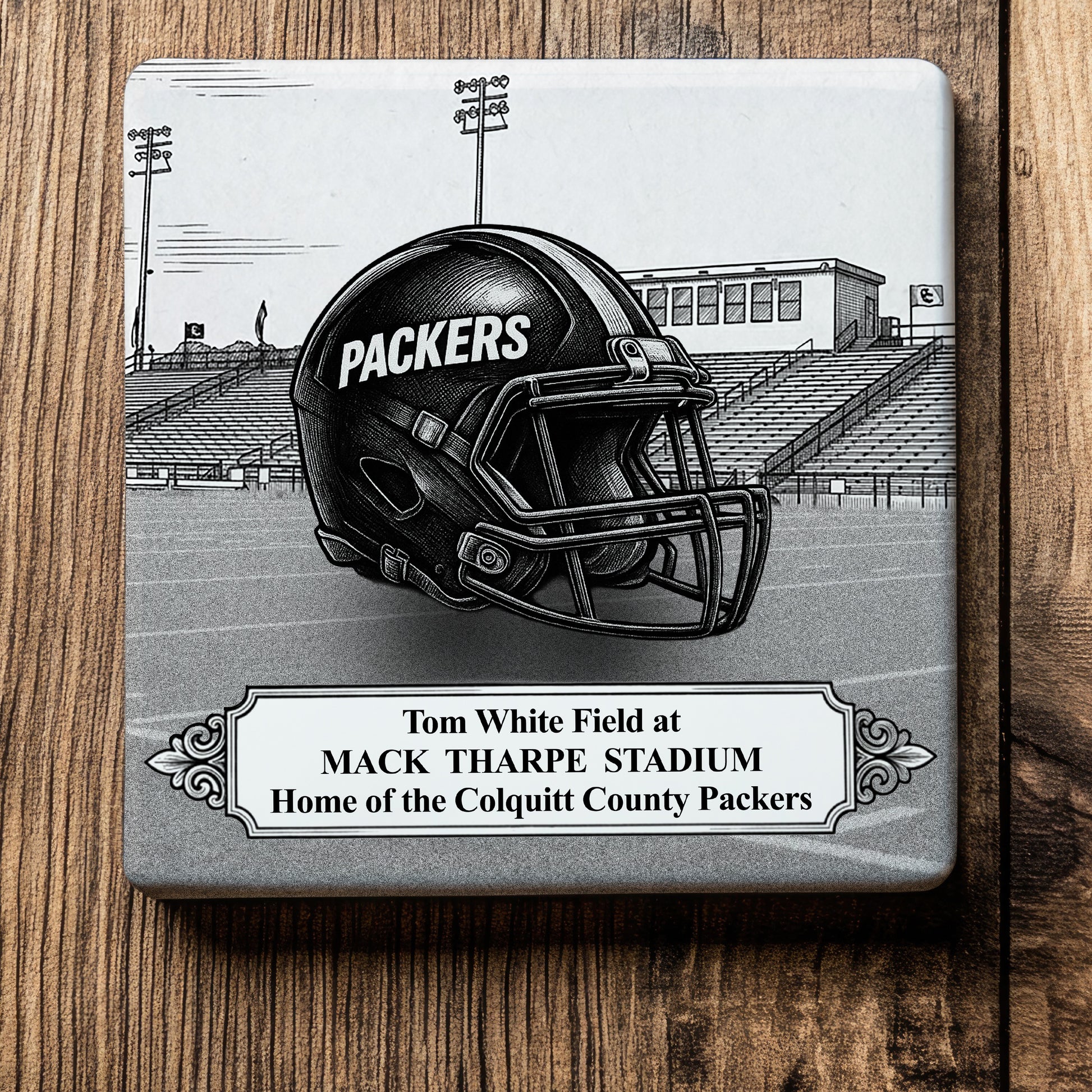 Ceramic drink coaster featuring a detailed black-and-white illustration of a Colquitt County Packers football helmet on Tom White Field at Mack Tharpe Stadium in Moultrie, Georgia.