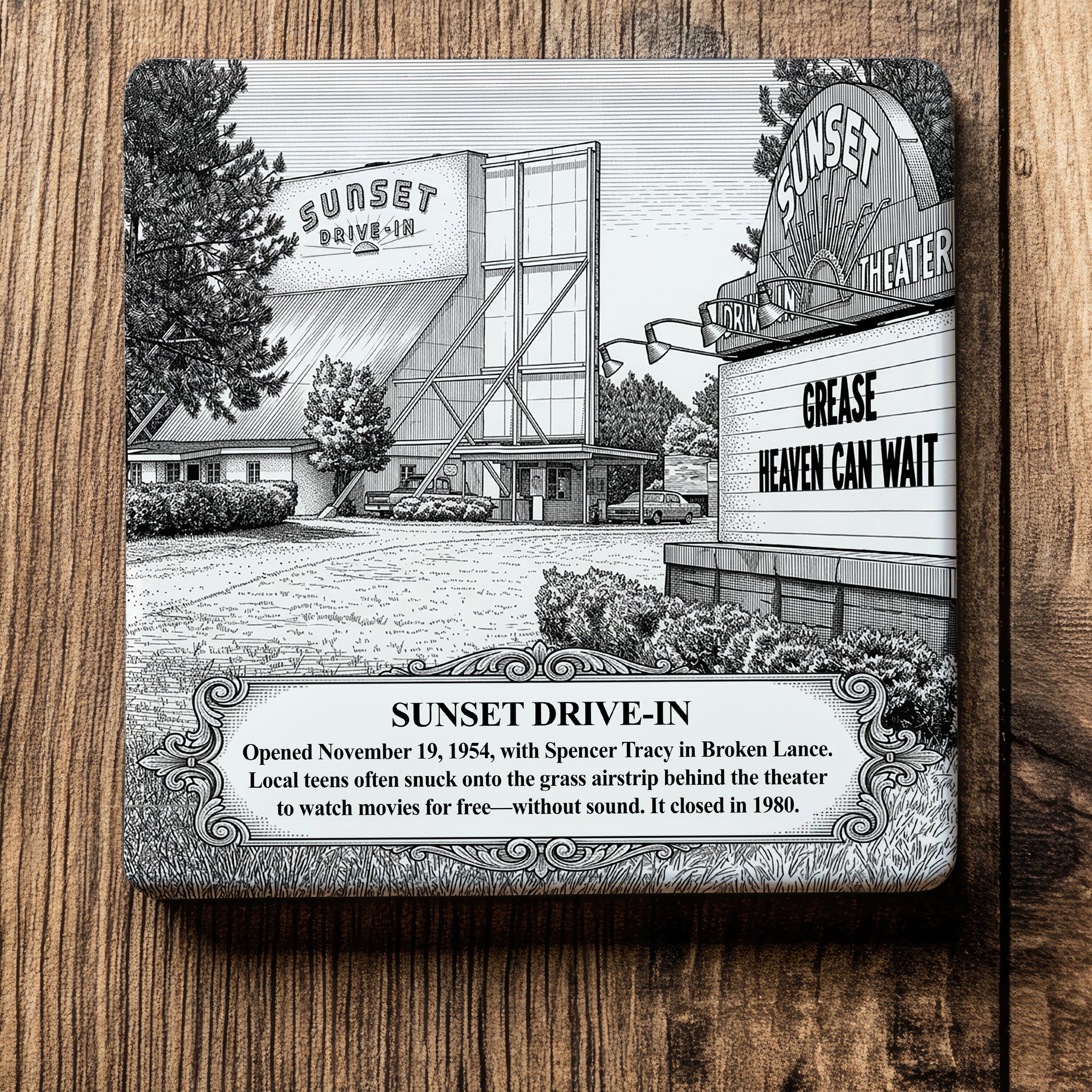 White ceramic coaster with a vintage pen-and-ink engraving of Sunset Drive-In Theater in Moultrie, Georgia. Features the screen tower, a roadside marquee displaying "GREASE," and an ornate historical text banner, flat on a wood grain surface.