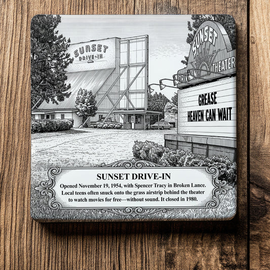 White ceramic coaster with a vintage pen-and-ink engraving of Sunset Drive-In Theater in Moultrie, Georgia. Features the screen tower, a roadside marquee displaying "GREASE," and an ornate historical text banner, flat on a wood grain surface.